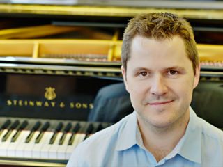 Portrait de Julien Bret avec un piano à queue Steinway & Sons à l’arrière-plan